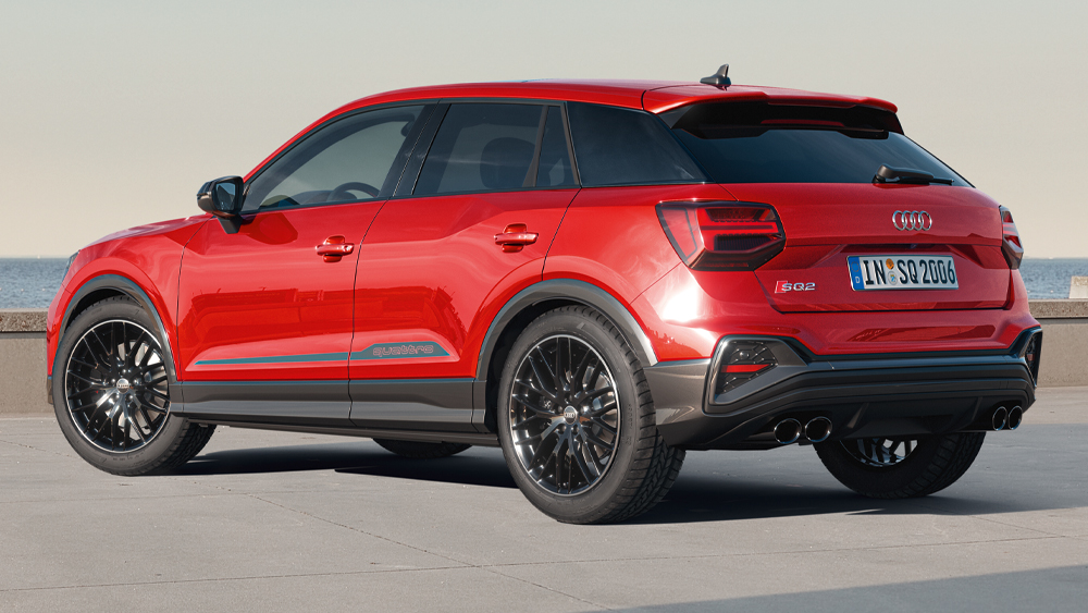 Audi SQ2 steht in roter Lackierung am Wasser, sportliches SUV-Design mit breiter Spur, schwarzen Rädern und markantem Heck