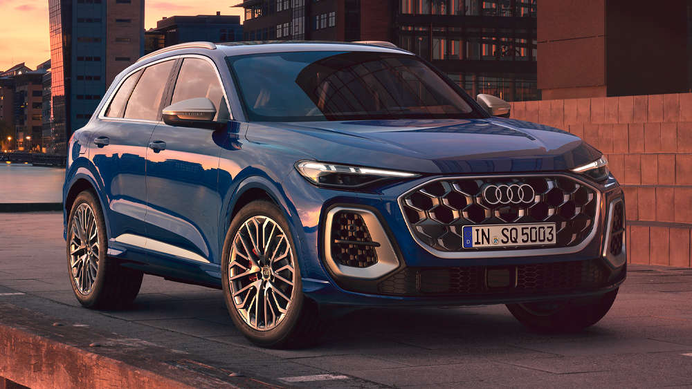 Audi SQ5 in Blau bei Dämmerung vor urbaner Architektur, markanter Singleframe-Grill, sportliche SUV-Frontansicht
