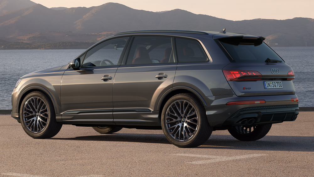 Audi SQ7 steht seitlich am Wasser vor Bergkulisse, markantes SUV-Design mit großen Rädern und kraftvollen Proportionen