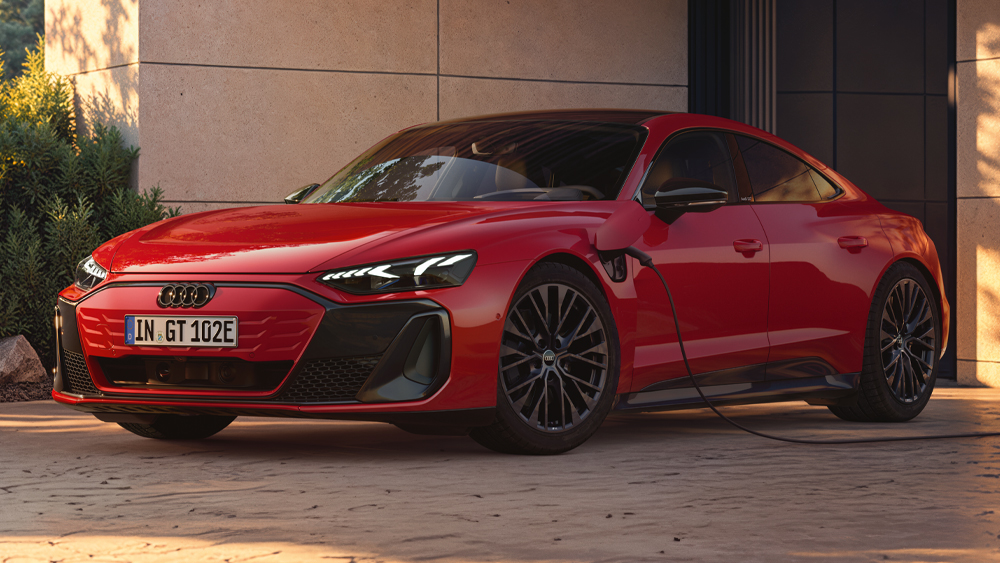 Roter Audi e-tron GT parkt vor moderner Architektur, sportliche Coupé-Silhouette mit breiter Front und großen Leichtmetallrädern