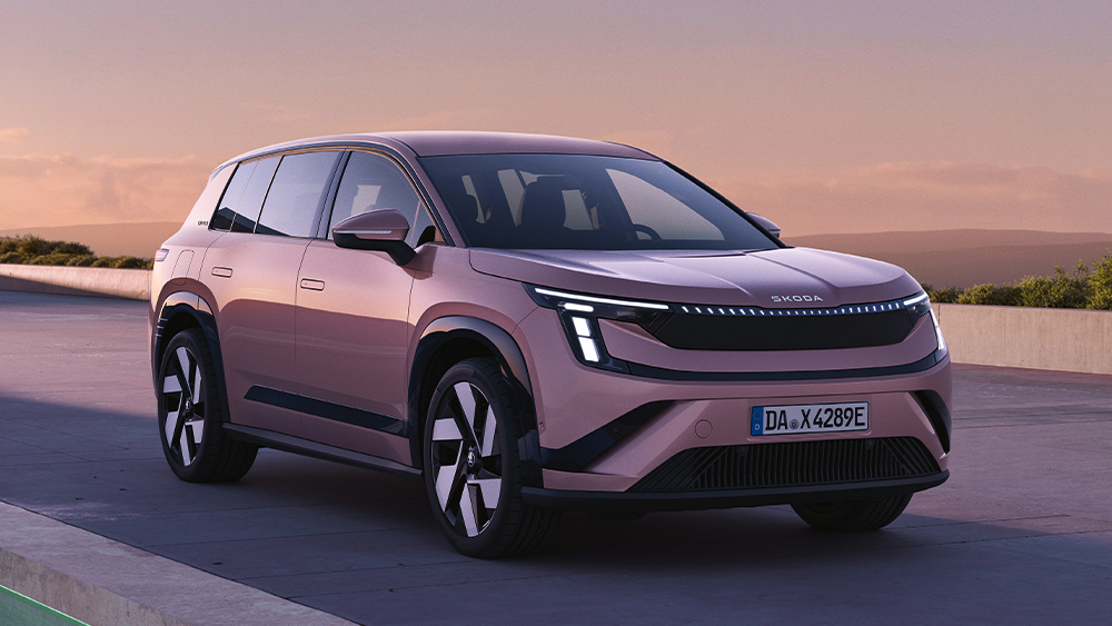 Neuer vollelektrischer Škoda Peaq auf einer modernen Terrasse vor Berglandschaft bei Sonnenuntergang.