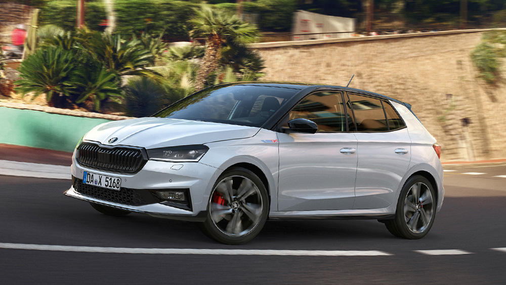 Škoda Fabia 130 Sonderedition in Weiß fährt durch eine kurvige Straße mit Palmen und Steinmauer im Hintergrund