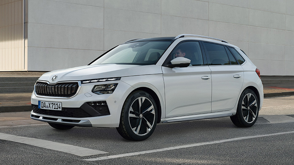 Škoda Kamiq in Weiß steht auf einer städtischen Straße vor moderner Gebäudefassade.