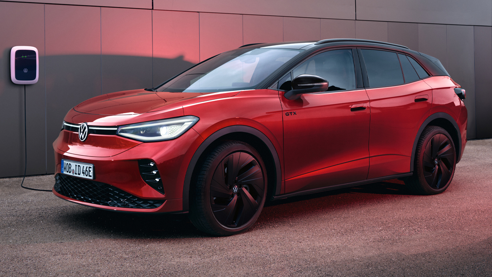 Volkswagen ID.4 in Rot wird an einer Wallbox vor einem modernen Gebäude geladen