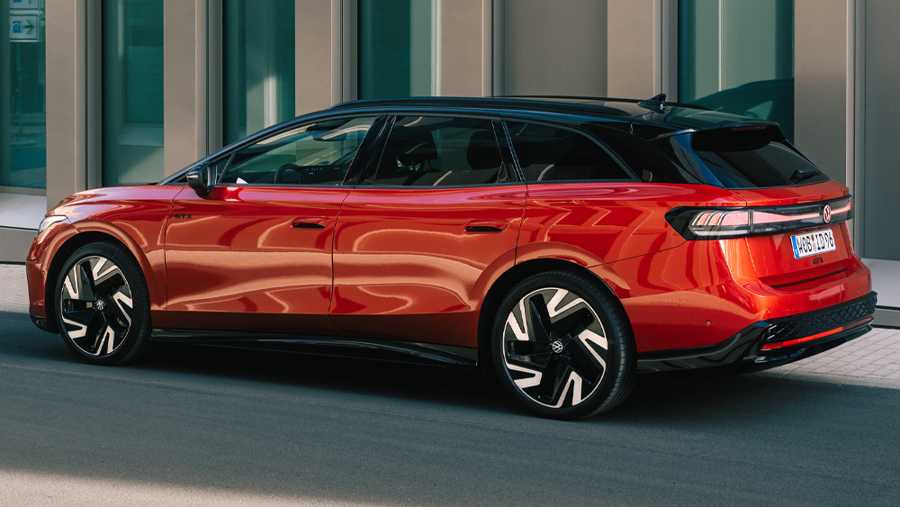 Roter VW ID.7 GTX Tourer mit schwarzem Dach steht seitlich vor moderner Architektur im Stadtumfeld