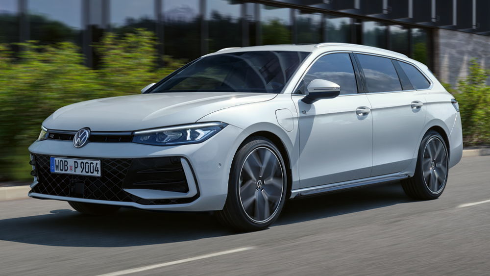 Weißer Volkswagen Passat Variant fährt dynamisch auf Straße vor moderner Architektur, Seitenansicht in Bewegung