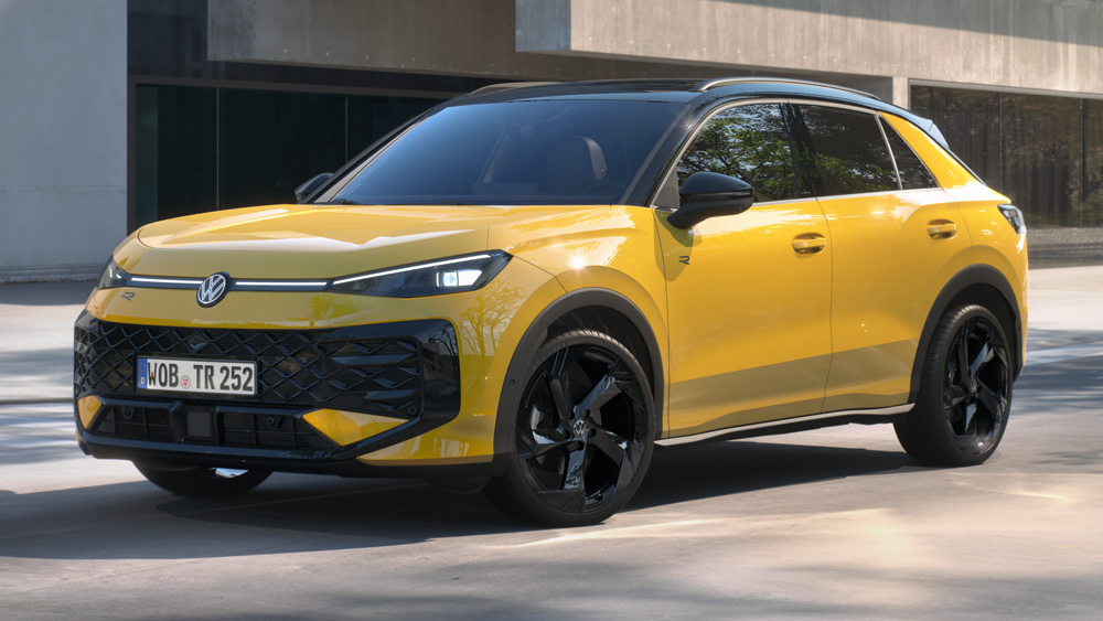 Gelber Volkswagen T-Roc mit schwarzen Leichtmetallrädern steht vor moderner Architektur im urbanen Umfeld