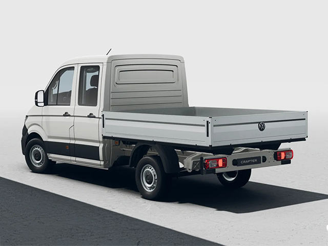 Weißer Volkswagen Crafter Pritschenwagen aus schräger Heckansicht auf heller Fläche vor neutralem Hintergrund