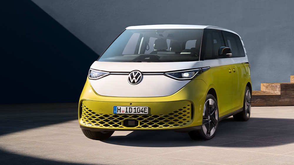 Zweifarbiger Volkswagen ID.Buzz steht vor modernem Gebäude, klare Formen und Tageslicht.