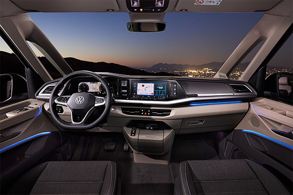 Innenraum des Volkswagen California mit Cockpit, Lenkrad und Display, gezeigt in moderner, beleuchteter Atmosphäre.