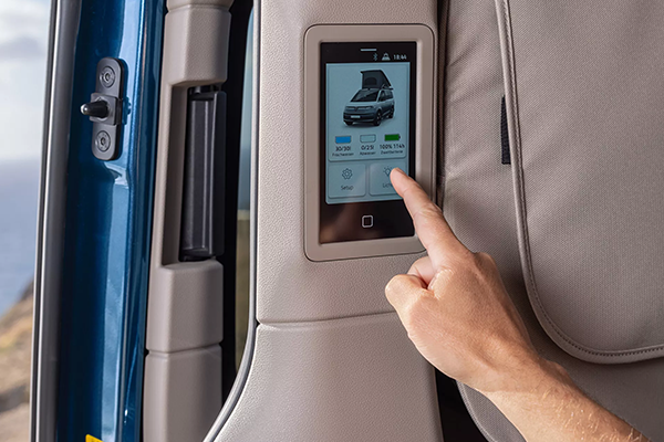 Detailansicht eines Touchdisplays im Innenraum des Volkswagen California, über das Campingfunktionen wie Licht und Fahrzeugstatus gesteuert werden.